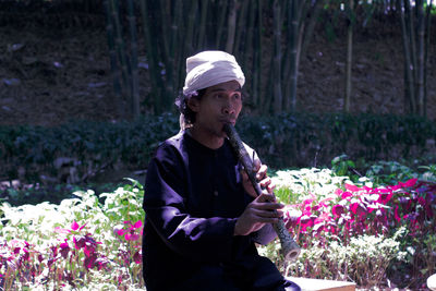 Man playing flute by plants