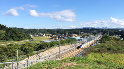 Train by houses on landscape against sky