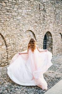 Rear view of woman dancing against white wall