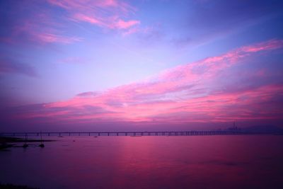 View of bridge over calm sea at sunset