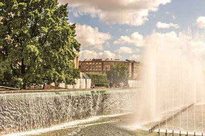 Fountain in city against sky