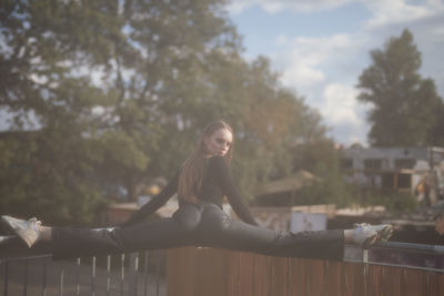 Low angle view of woman sitting on railing