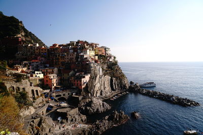 Aerial view of buildings by sea against clear sky