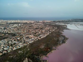 Aerial view of townscape by sea against sky