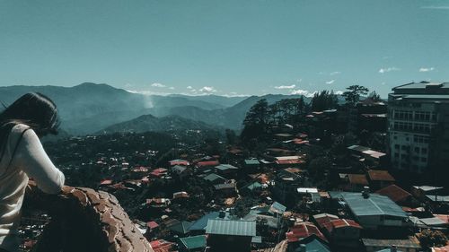 Midsection of woman standing by mountain against clear sky