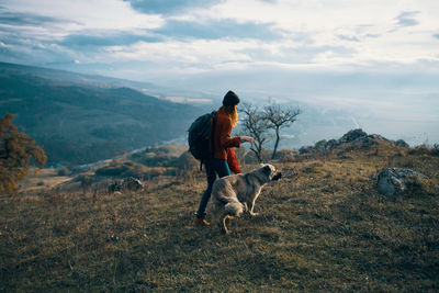 Woman with dog standing on mountain against sky