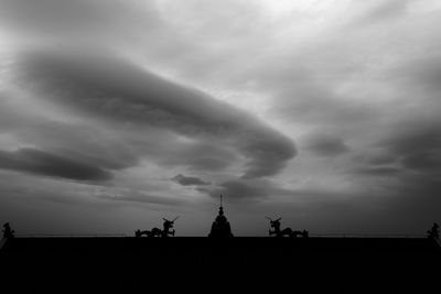 Low angle view of silhouette statue against cloudy sky