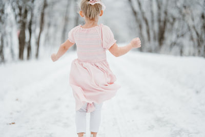 Portrait of young girl standing on snow covered field