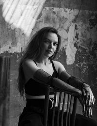 Portrait of young woman sitting against wall