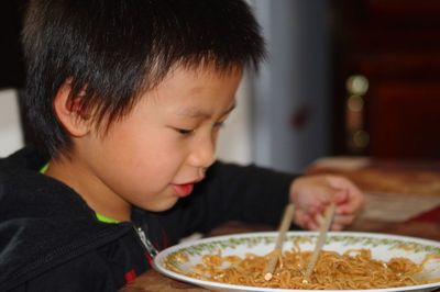 Boy by plate of noodles at home