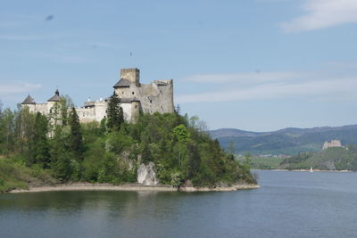 View of castle by river against sky
