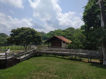 Empty benches by trees and buildings against sky