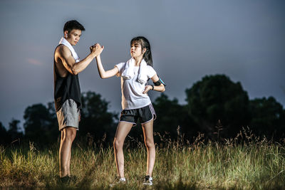 Full length of friends standing on field against sky