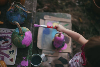 High angle view of girl painting pumpkin at backyard during halloween