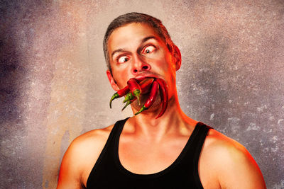 Portrait of mature man eating food against gray background