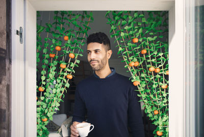 Young man holding coffee cup while walking through doorway