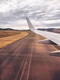 Airplane wing on runway against sky