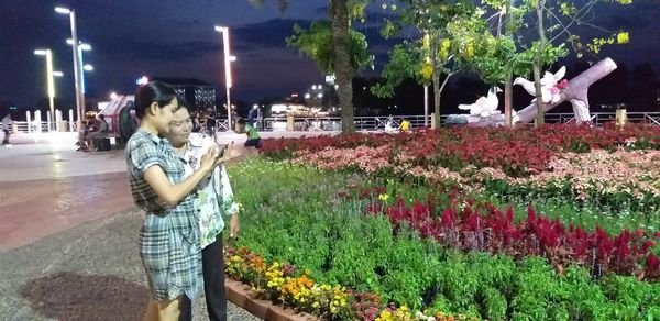 People standing by flowering plants in city