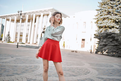 Full length of young woman standing against built structure