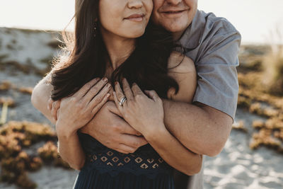 Husband tenderly hugging long-haired wife from behind