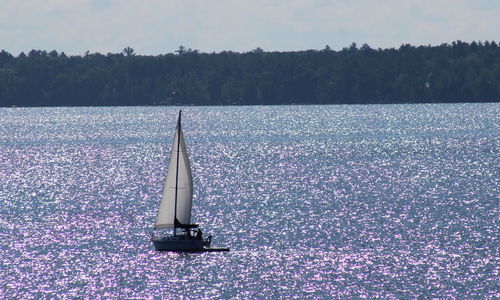 Sailboat in lake against sky