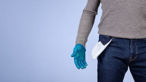 Midsection of man holding umbrella standing against blue sky