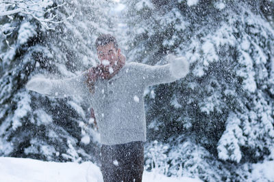 Smiling young man standing in forest during winter