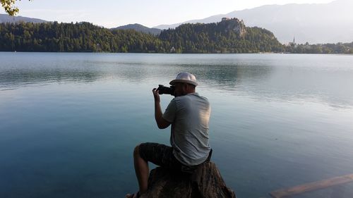 Man sitting by lake against mountain