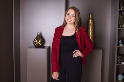 A cute girl in a jacket is standing in a dark office and smiling