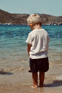 Rear view of boy standing at beach