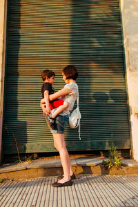 Mother carrying son while standing by shutter