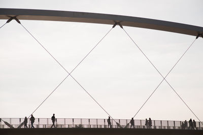 Silhouette people walking on hoge brug bridge against clear sky