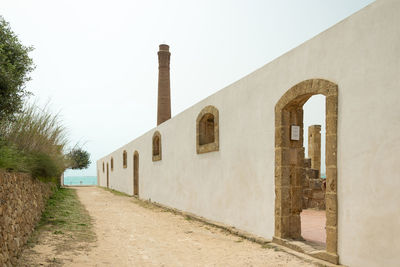 Footpath amidst buildings against clear sky