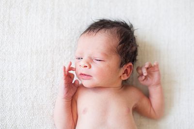 High angle view of shirtless cute baby boy lying on bed