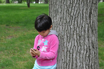 Front view of girl leaning on tree trunk