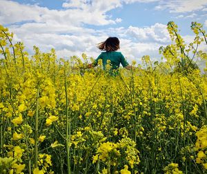 Low angle view of woman amidst plants on field against sky