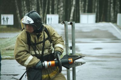 Firefighter holding equipment while standing on road