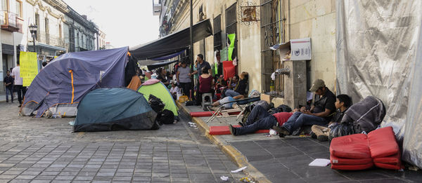 People sitting on footpath against buildings in city