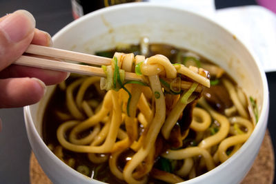 Close-up of hand holding noodles in bowl