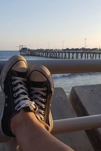 Low section of man on bridge over sea against sky