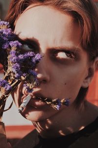 Close-up portrait of young woman with purple flower