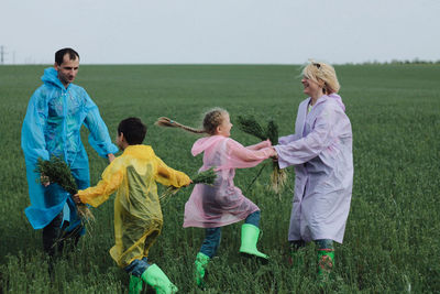 Siblings standing on field against clear sky