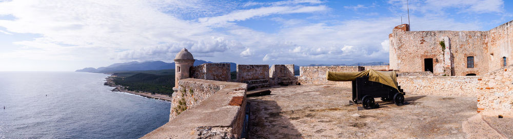 Old building by sea against sky