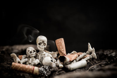 Close-up of human hand holding cigarette against black background