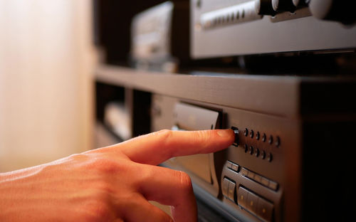 Person is pressing a button to open the disc tray. listening to music with a compact disc player