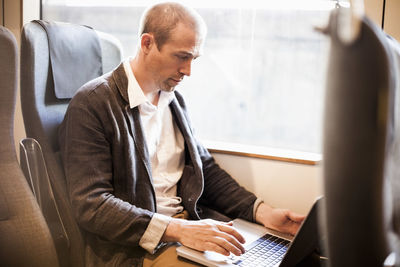 Mature businessman using laptop in train