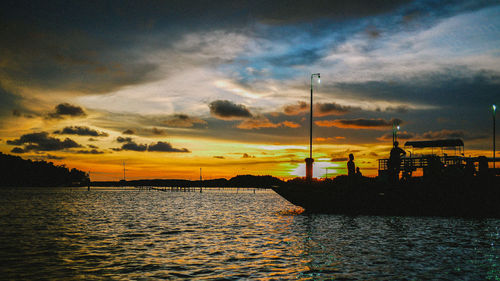 View of calm river against cloudy sky at sunset