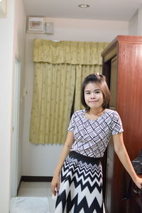 Portrait of young woman with short hair standing at home