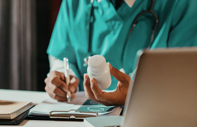 Midsection of doctor using laptop at table