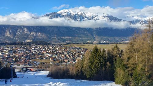 Scenic view of ski slope by mountains against sky